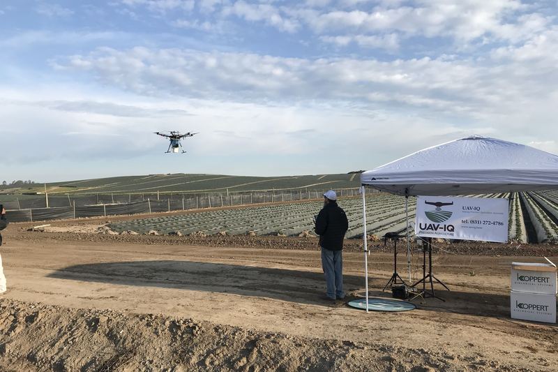Drone flying over farmland during a field operation, with a support tent on the ground